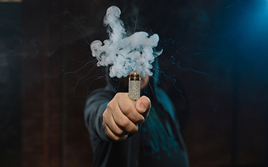 Dripper in one hand making a cloud of white, blue vapours. Friendly for vape shop posters and design. Vaping concept.